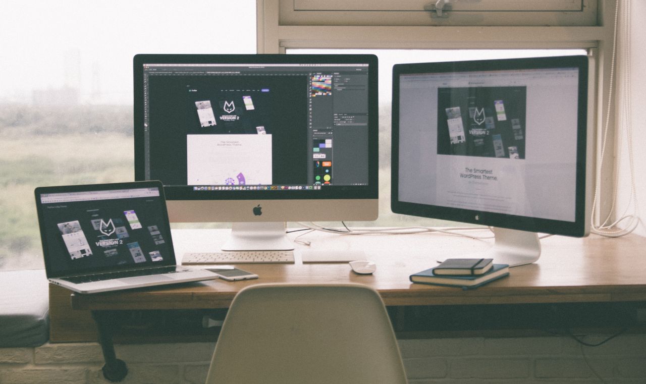 about-01 Stylish and efficient workspace with multiple monitors, laptop, and smartphone, showcasing a web design project.